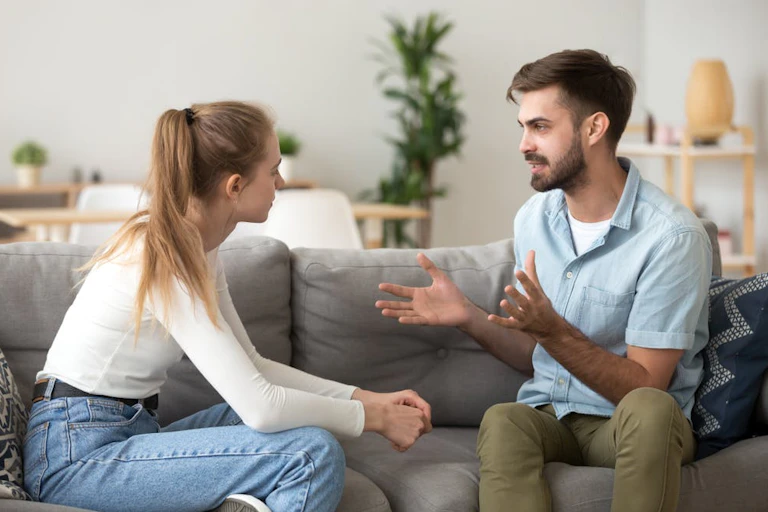 Young woman and man sit on a sofa talking