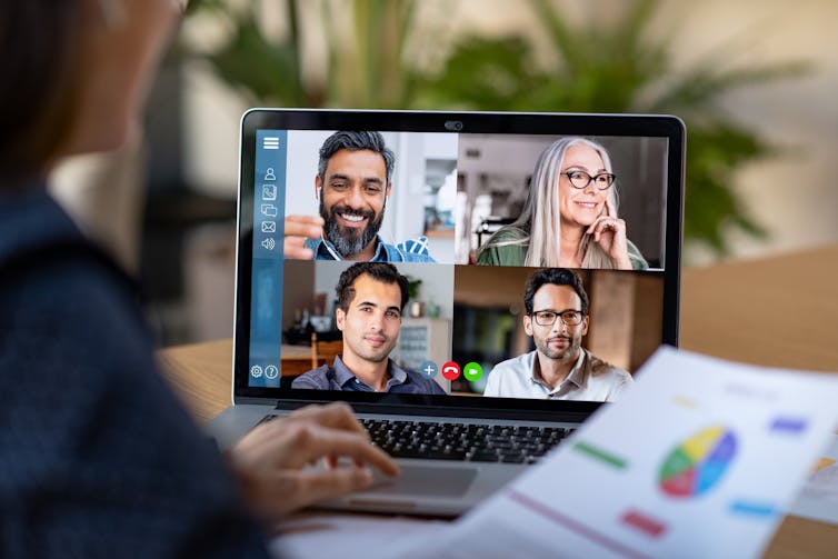 Back view of business woman talking to colleagues on a video call.