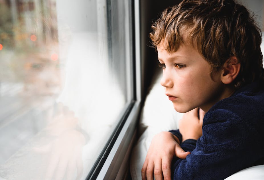 A young boy looks out of a window.