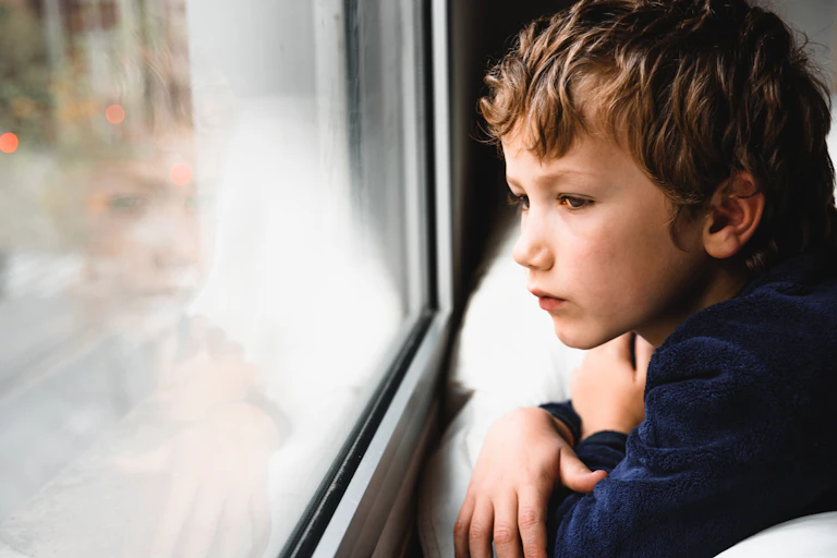 A young boy looks out of a window.