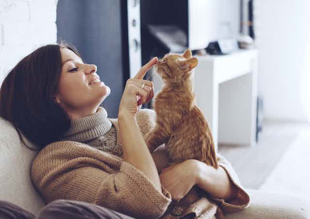 A woman playing with her pet cat.