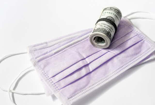 a roll of $100 bills on top of surgical masks