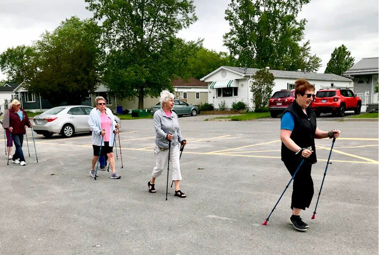 Four Oasis members pole walking through their mobile home community