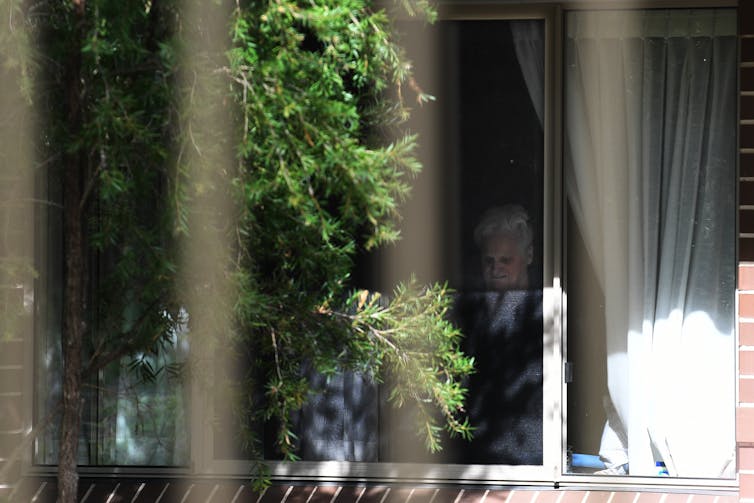 Resident of Newmarch House aged care facility looks out her window during the COVID-19 pandemic.