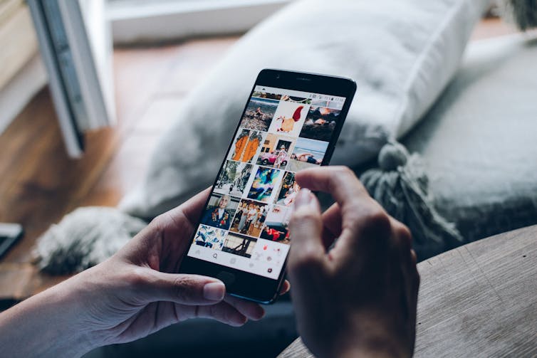 Woman's hands holding a smart phone with Instagram images.