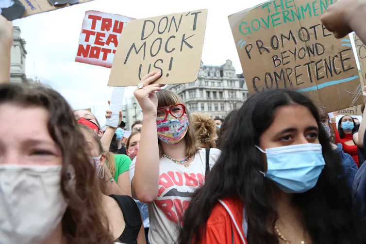 Teenage protestors wearing masks and holding signs.