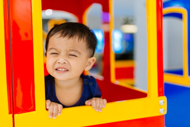 Young boy playing in a cubby house.
