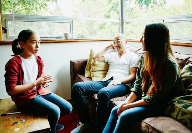 girl talking to two adults at home