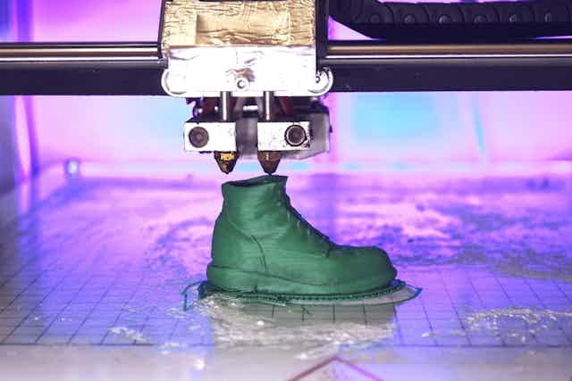 Máquina de impresión 3D imprime una bota verde.