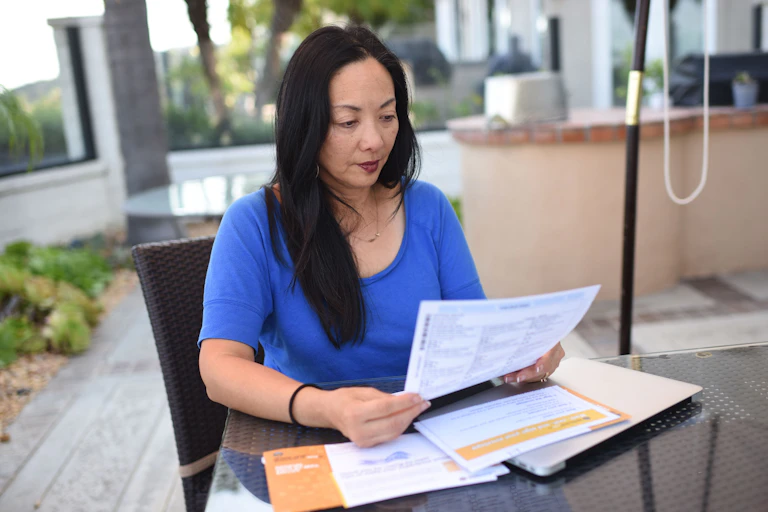 A woman at home holding an absentee ballot.