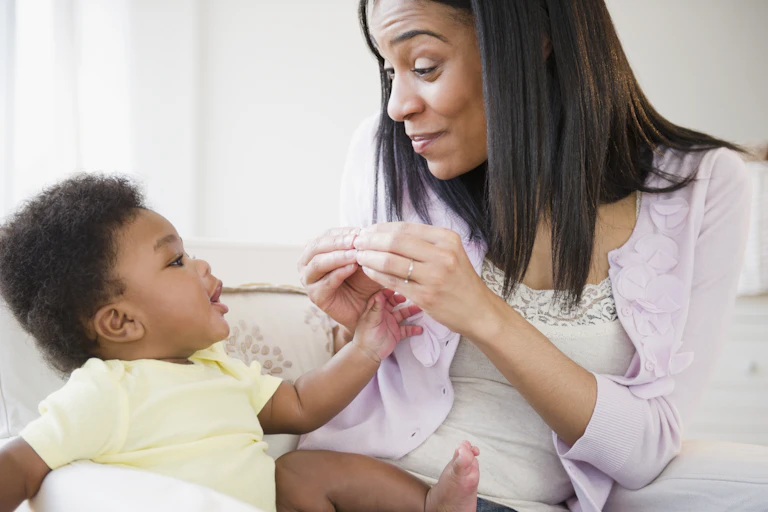 African American mother signing to baby boy by putting her fingertip together.