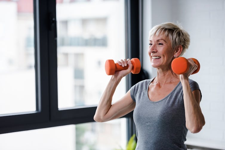 An elderly lady lifting some small weights at home