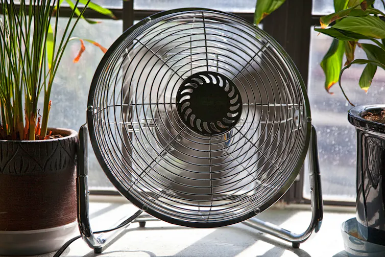 A spinning fan sits on a windowsill.