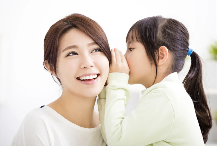 Girl whispers into woman's ear