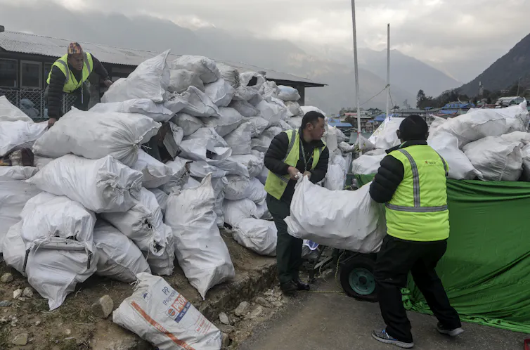 Men loading bags of rubbish onto vehicle.