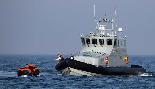 A UK Border Force boat meets a small boat in the English Channel.
