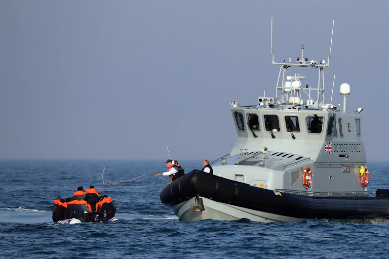 A UK Border Force boat meets a small boat in the English Channel.