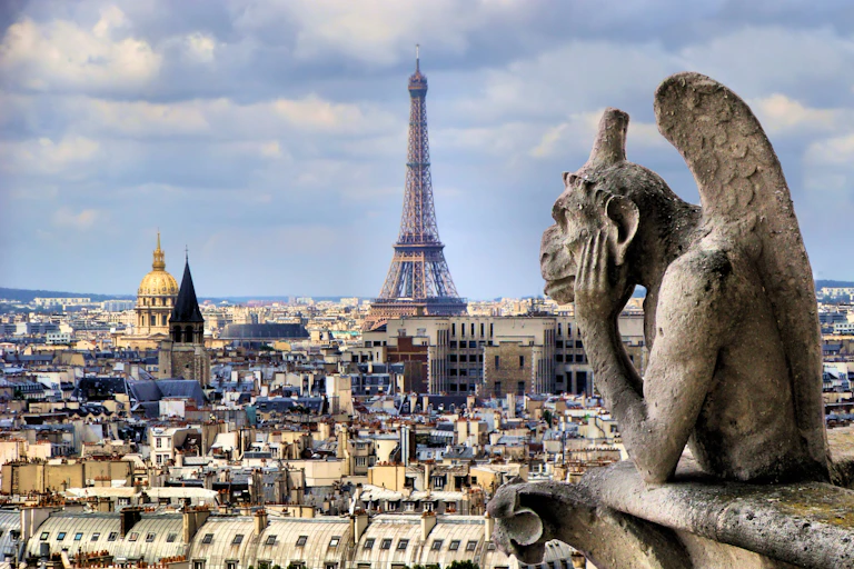 Stone gargoyle looking out over Paris and the Eiffel Tower.