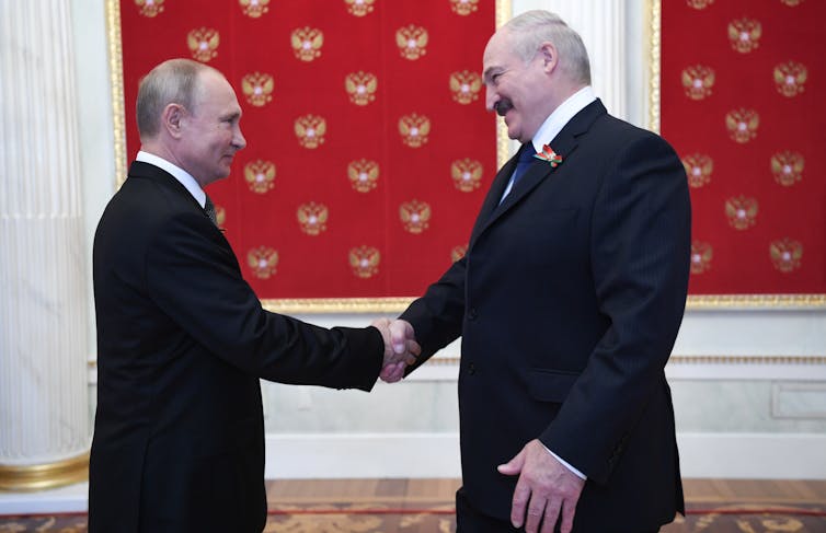 Vladimir Putin and Alexander Lukashenko shaking hands.