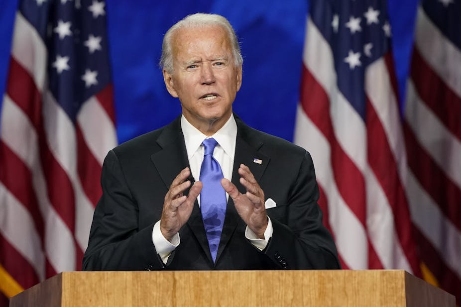 Biden stands at a podium flanked by American flags.