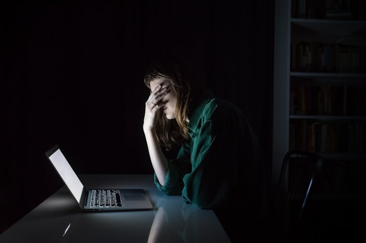 Tired women using laptoop at night.