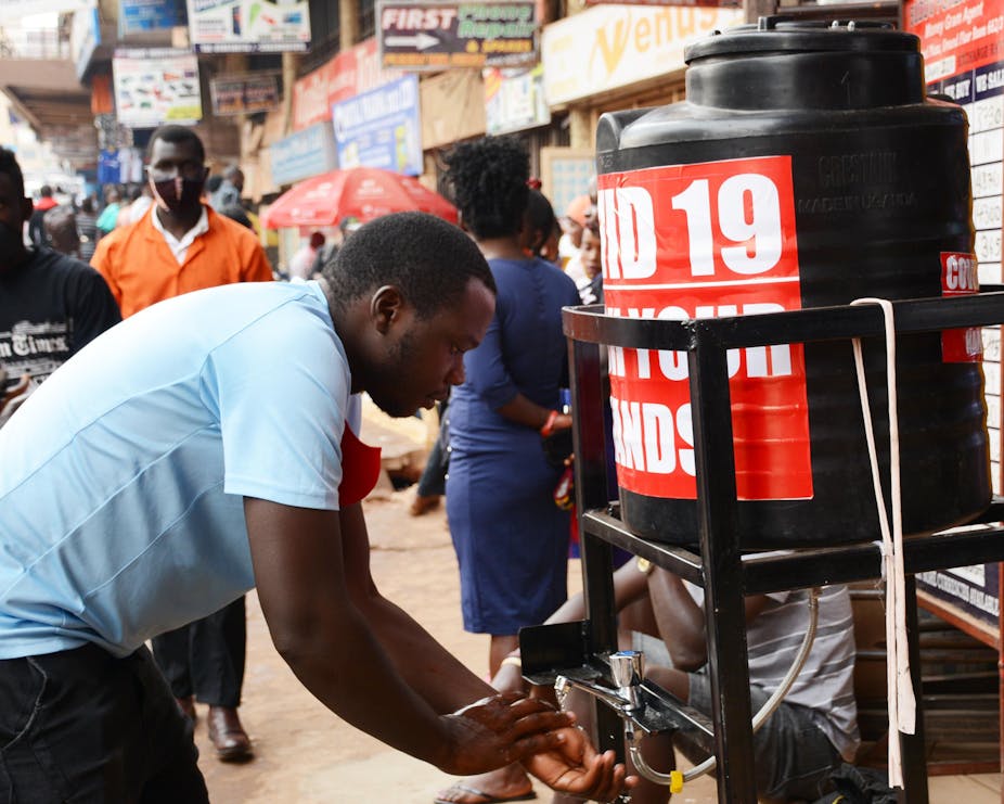 Man washing his hands at a disinfection station on the street