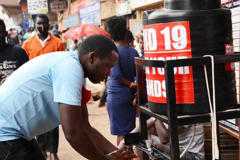 Man washing his hands at a disinfection station on the street