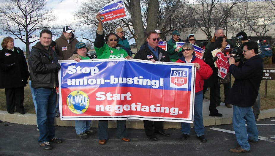 Protesters carry a sign addressed to Rite Aid that reads "Stop union-busting! Start negotiating."
