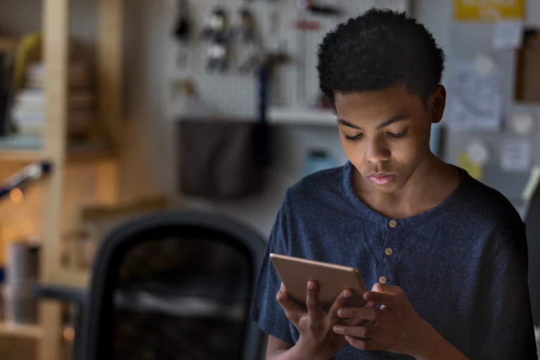Boy plays game on digital tablet at home.