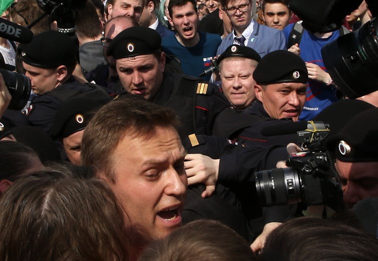 Riot police arresting opposition leader Navalny.