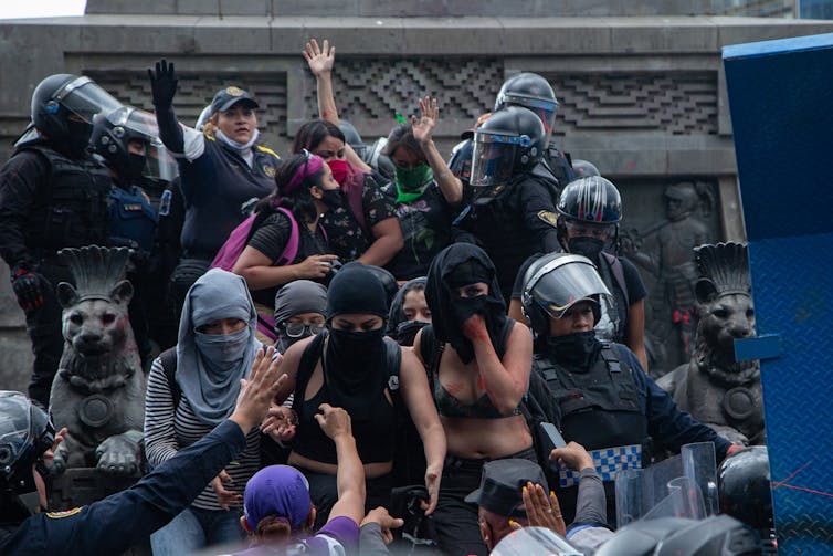Women dressed in black and wearing face masks clash with police in Mexico CIty