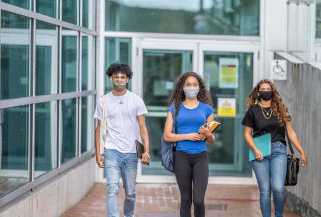Three students walk on a college campus