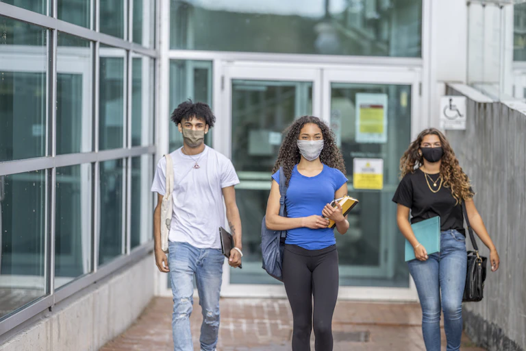 Three students walk on a college campus
