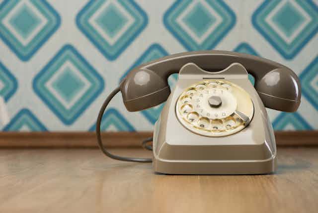Retro phone on wooden floor with retro geometric wallpaper in background