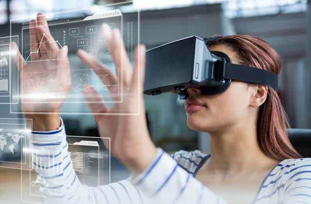 A student in a VR headset touches a screen.