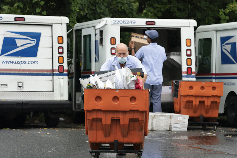 Letter carriers load mail trucks for deliveries at a U.S. Postal Service facility in McLean, Va.