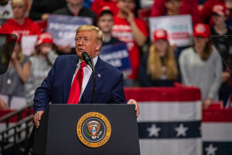 President Donald Trump speaking with crowd behind him