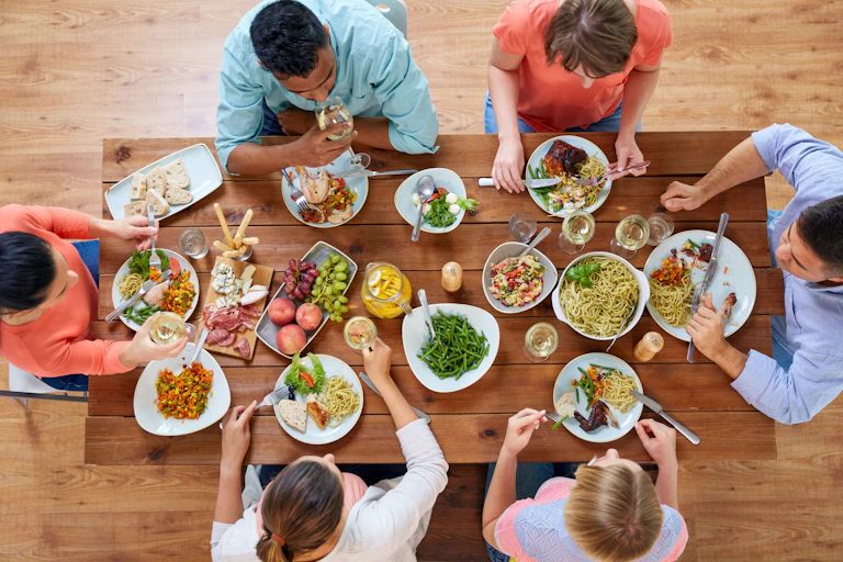 Group of friends eating large meal at a dinner table.