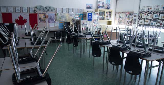 Chairs are seen on desks in an empty and dark classroom.