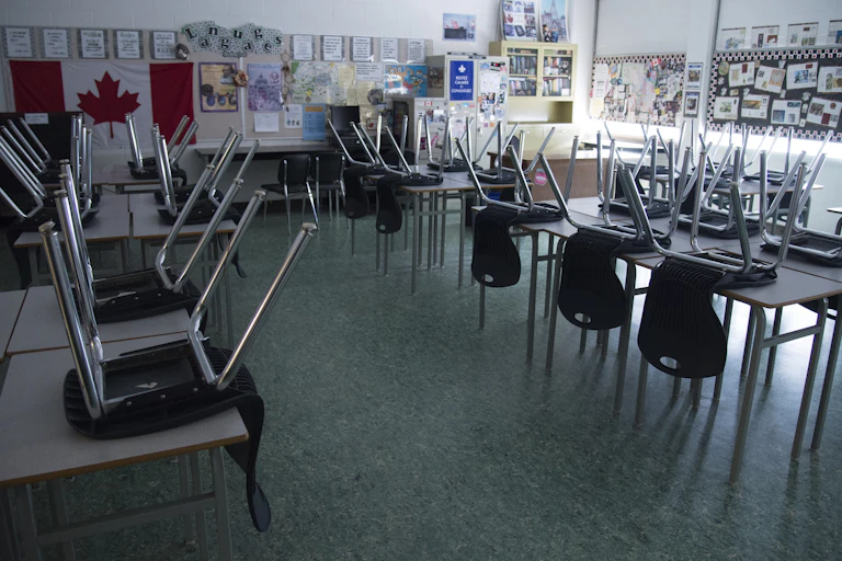 Chairs are seen on desks in an empty and dark classroom.