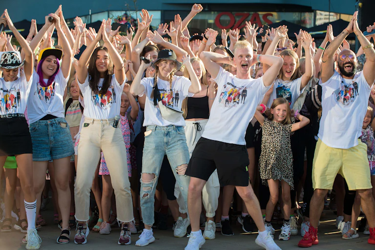 A group of young people dance with their arms in the air