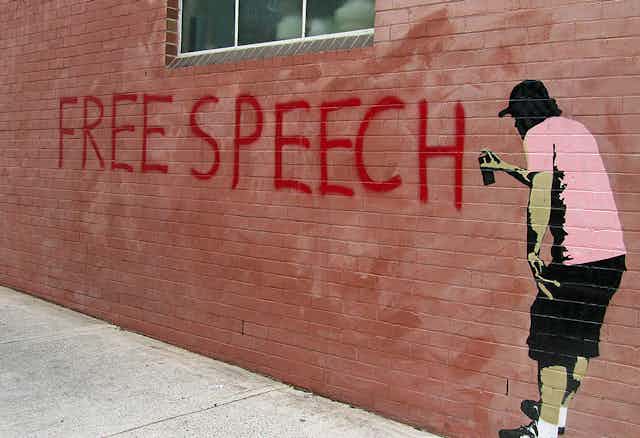 Mural of man spray-painting 'FREE SPEECH' on wall