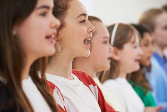 Young girls singing in a row, from the side