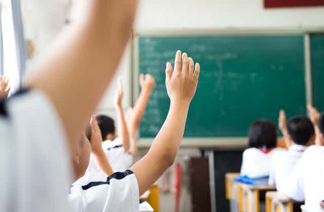Classroom scene with hands raised. 