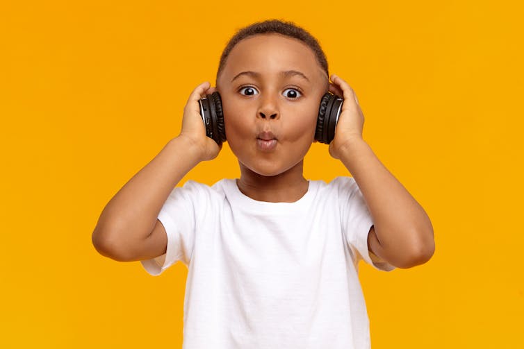 Young boy wearing headphones and whistling.