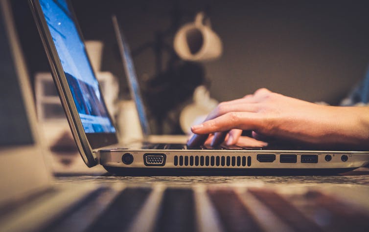 Hands typing on a laptop