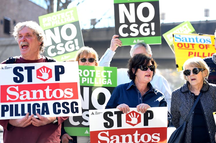 Protesters hold placards against Santos