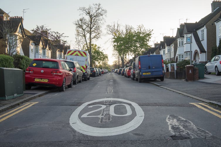 Suburban road with a 20mph speed limit sign painted on the tarmac.