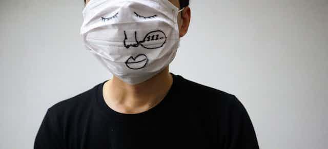 Una persona luce una mascarilla que le tapa toda la cara dibujada con ojos, nariz y boca.