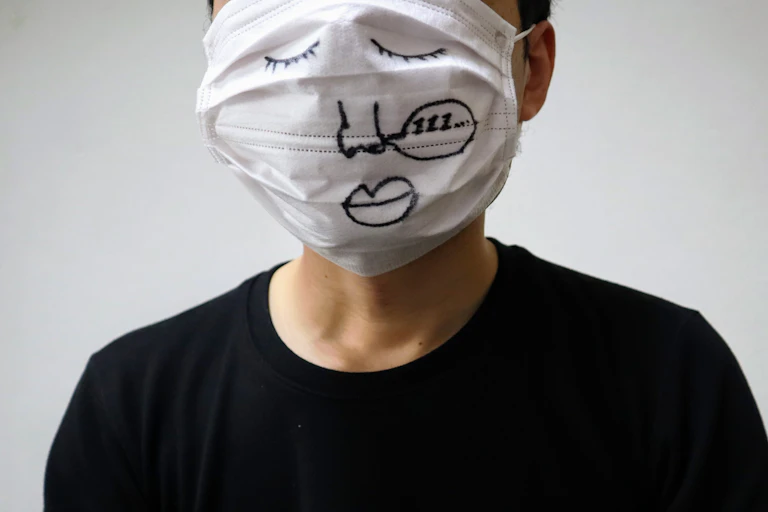 Una persona luce una mascarilla que le tapa toda la cara dibujada con ojos, nariz y boca.